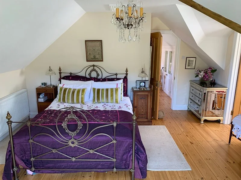Kittiwake's king-size master bedroom with iron bed, wooden floor and balcony doors