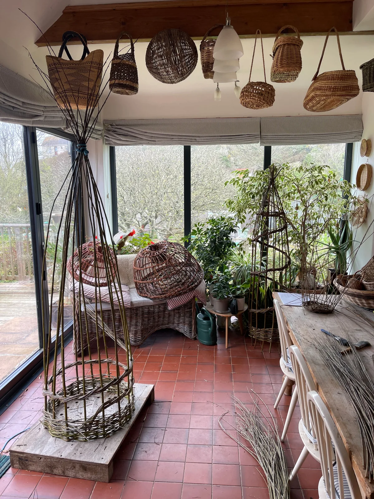 Sue's willow workspace at Kittiwake, with baskets, crab pots, willow frames and bundles of withies