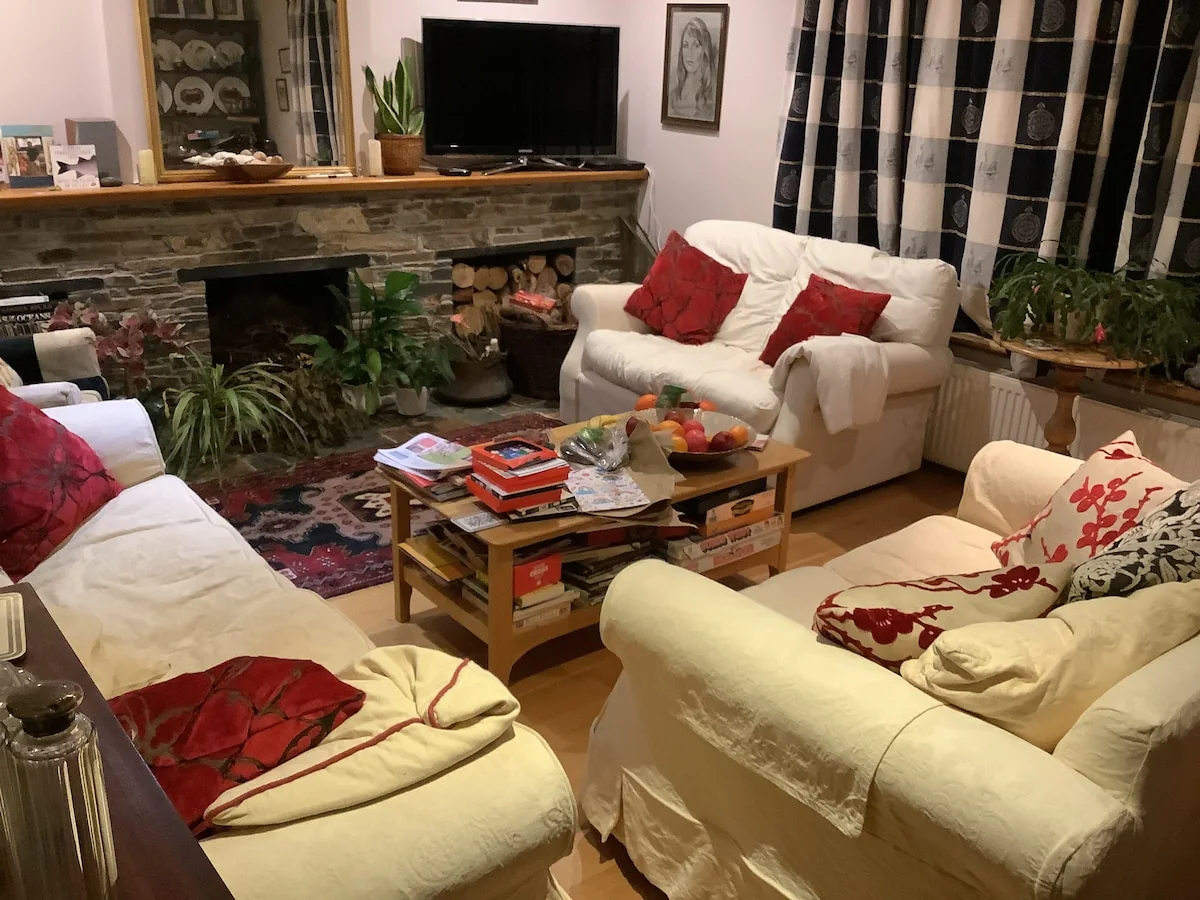 Family living room with three sofas, a stone fireplace and television