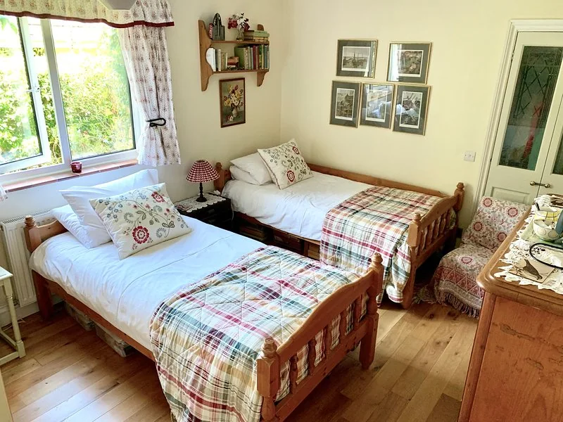 Twin bedroom with two single wooden beds and a garden view