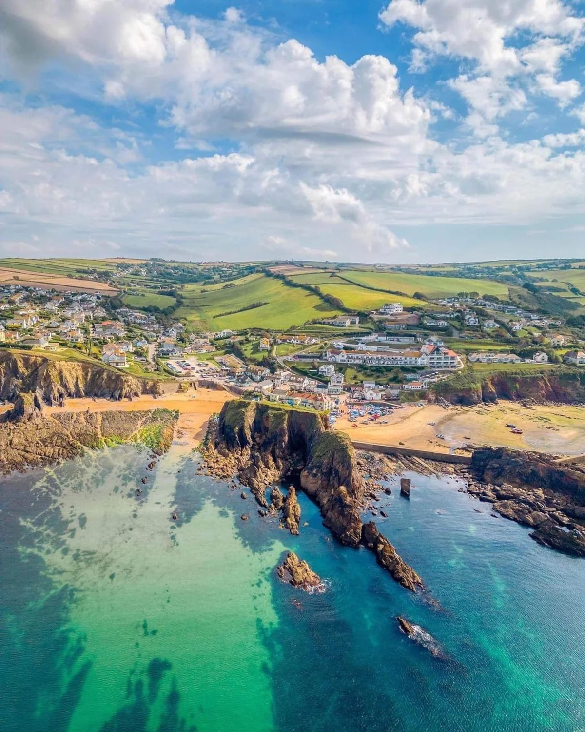 Aerial view of Hope Cove, with two sandy beaches, rocky headlands and green fields inland