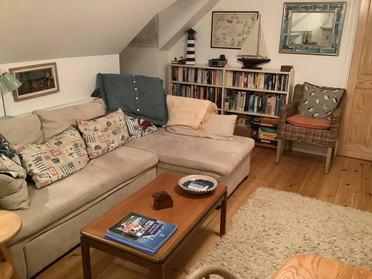 Upstairs sitting area at Kittiwake, with a corner sofa, books, games and nautical decorations